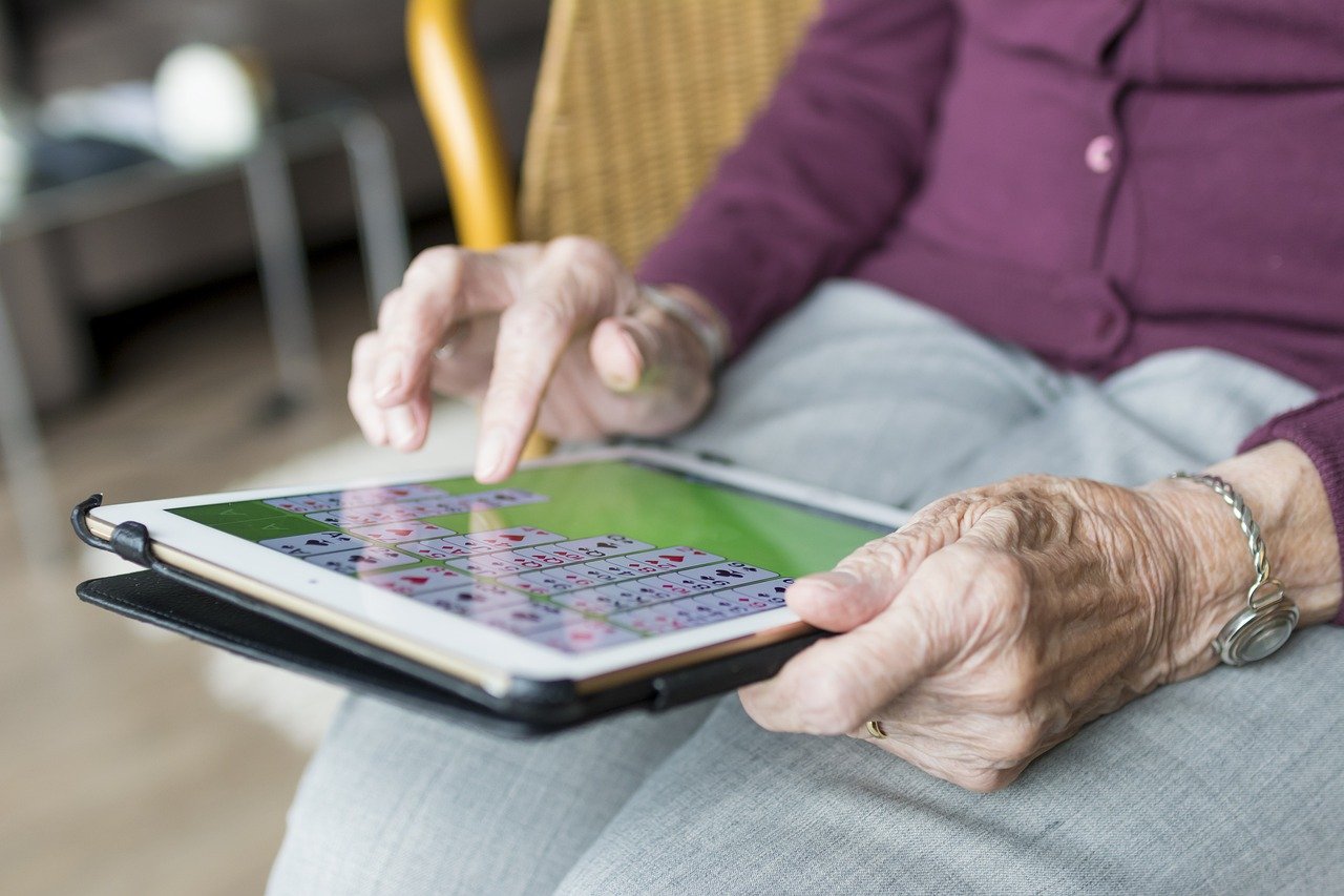 Elderly lady doing puzzles on a tablet. Dementia support.